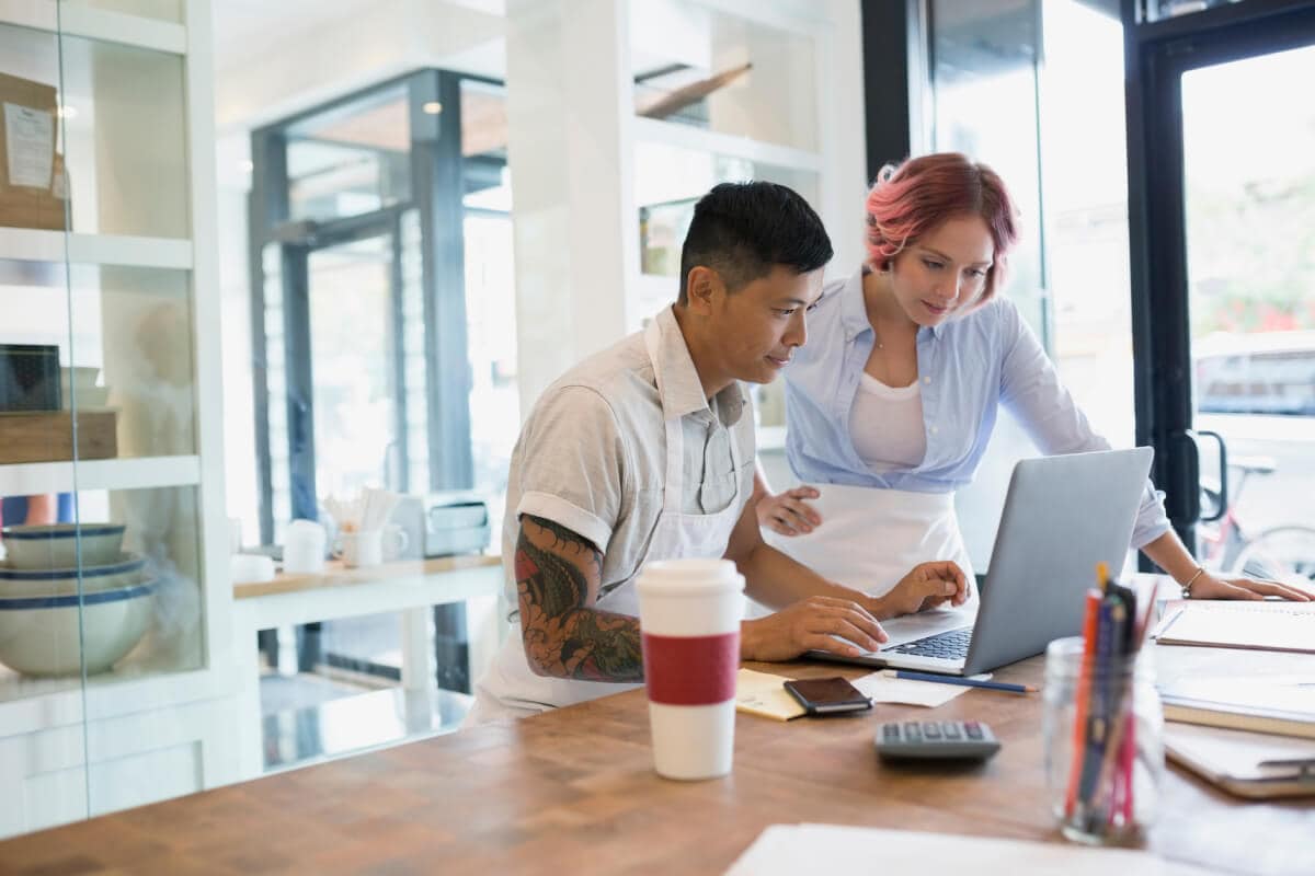 A couple in their 30s looking at a computer or tablet together.
