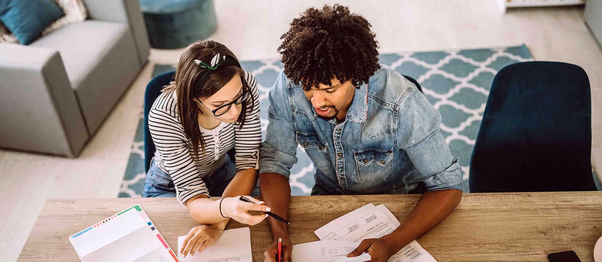 A man and woman seated at a table, reviewing documents related to conventional, conforming, and jumbo loans.