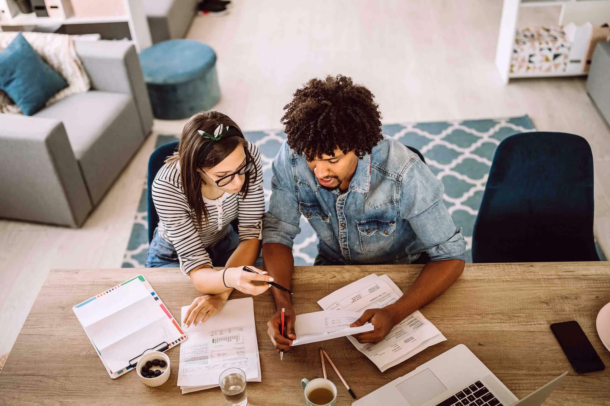 A man and woman seated at a table, reviewing documents related to conventional, conforming, and jumbo loans.