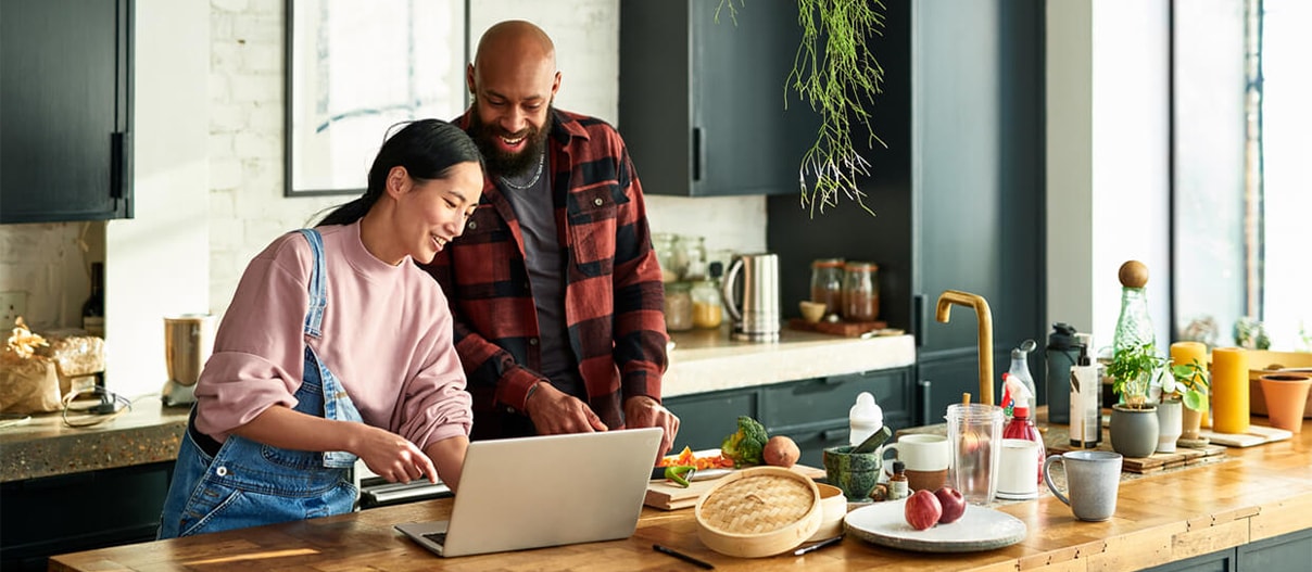 Couple at the kitchen table looking at a laptop