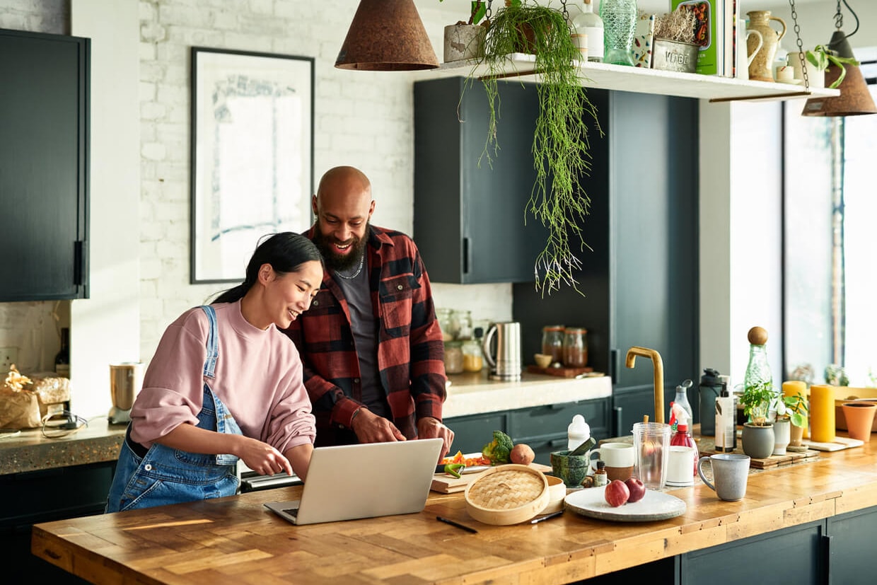Couple at the kitchen table looking at a laptop