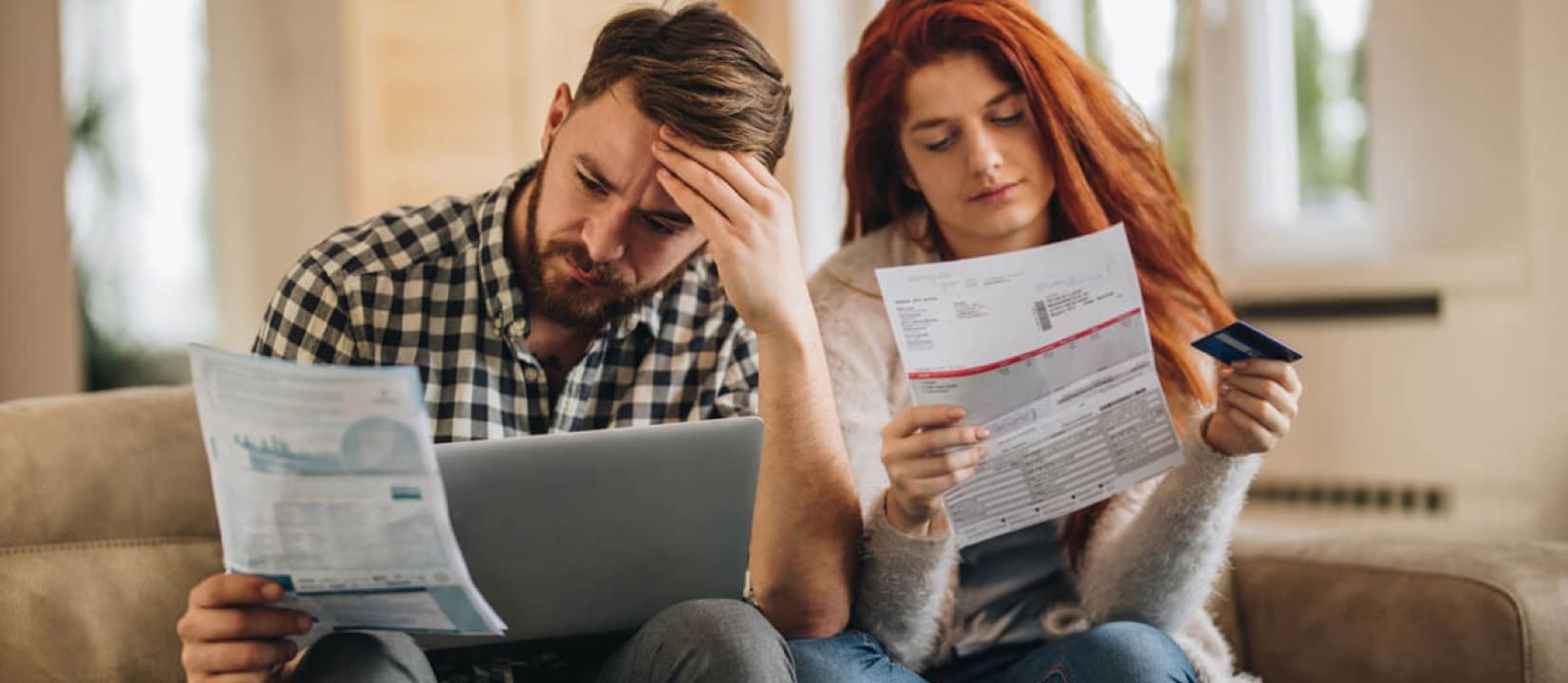 People holding some bills looking contemplative