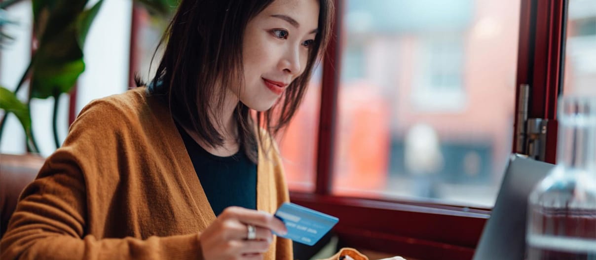 A person holding a credit card while using a laptop