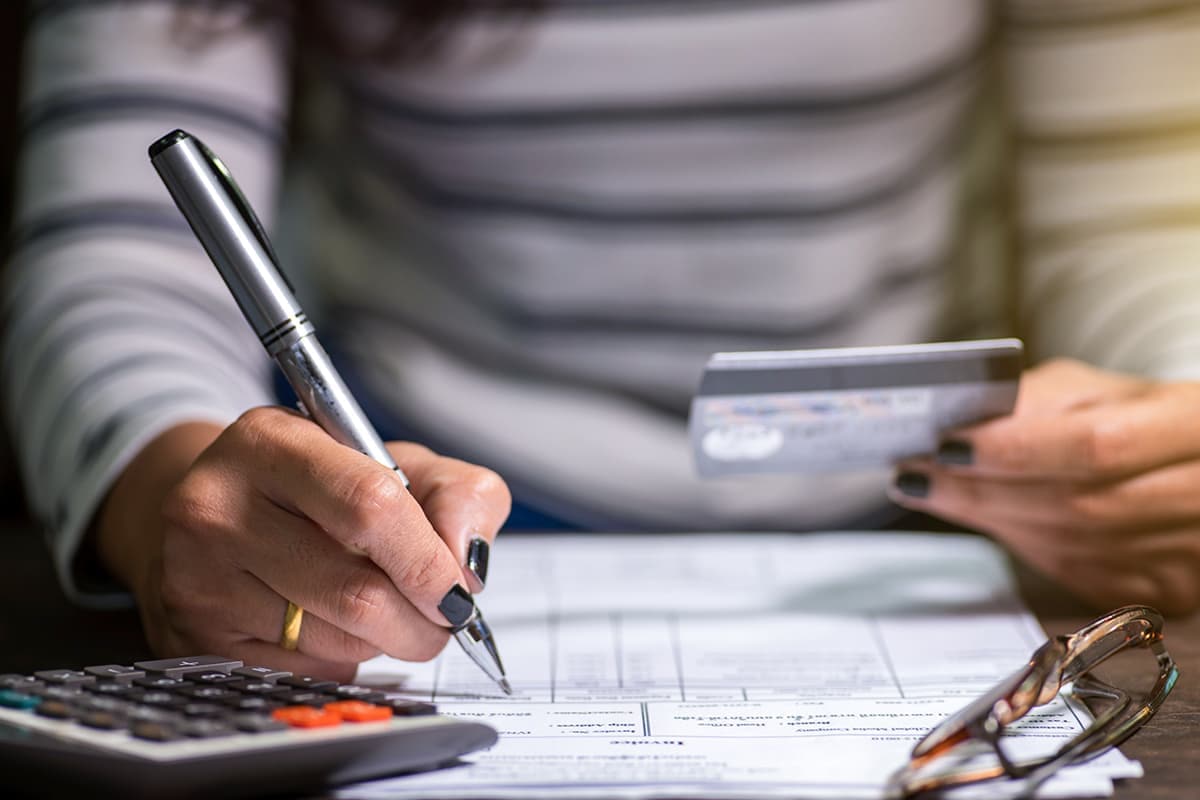 Someone using a calculator and holding a credit card.