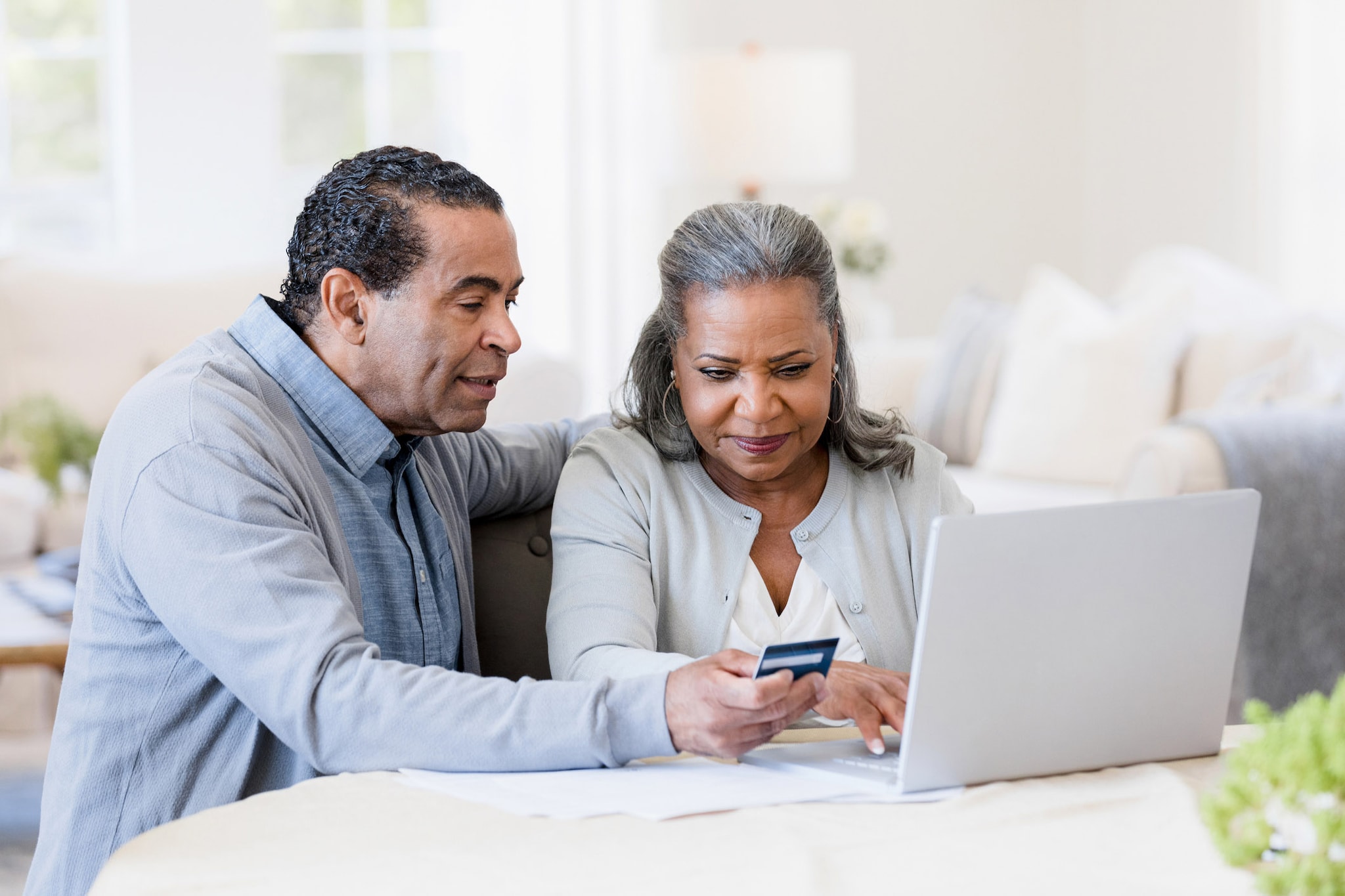 Elderly couple are paying bills with their credit card through their laptop