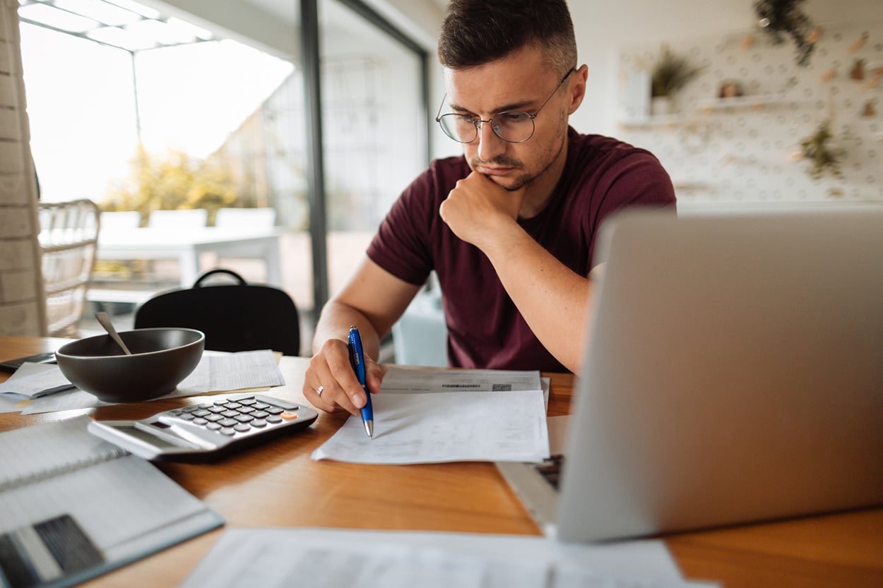 A man sits a his desk while signing paperwork