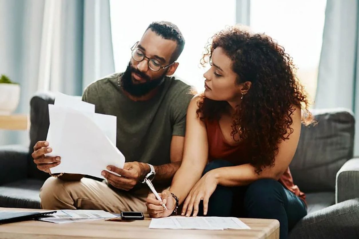 A man and woman examine a document together, discussing the importance of credit monitoring for financial health.