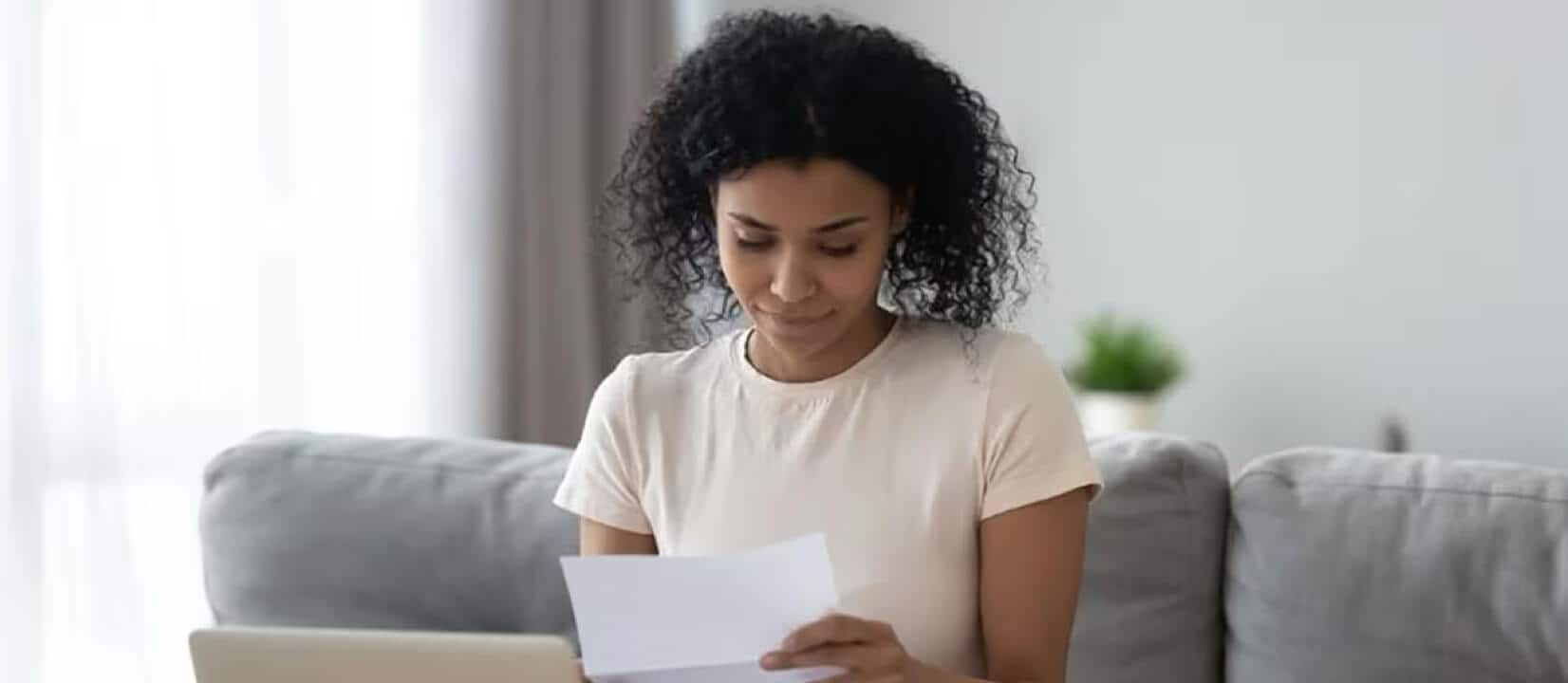 A woman sits on her couch looking at her credit score