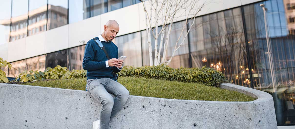 Man is outside, using his phone in day time