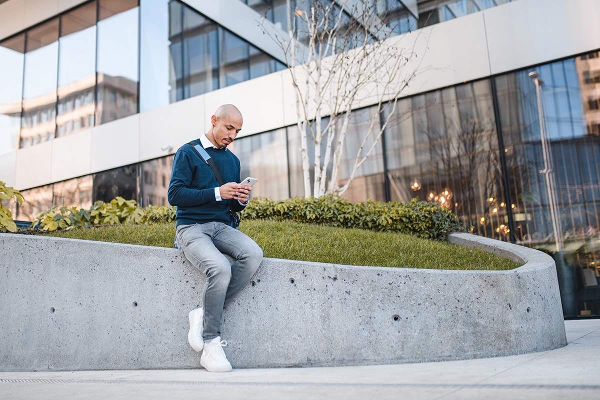 Man is outside, using his phone in day time