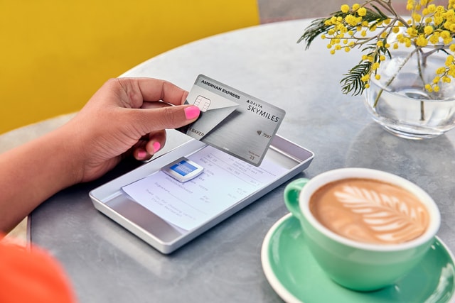 American Express Delta Skymiles Credit Card in the hand of a person that paying for a coffee