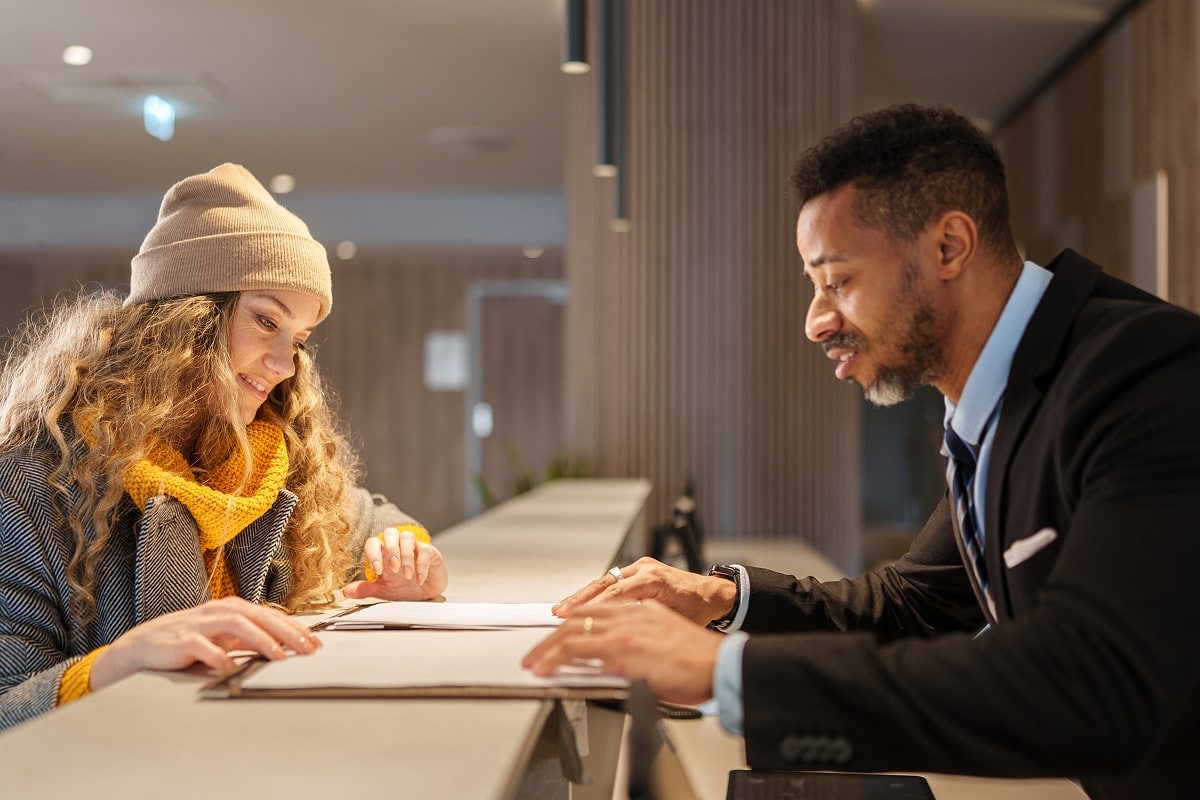 A professional image of a person at a bank counter, handing over a check to a teller, or someone endorsing a check.