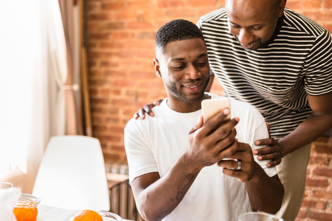Two men are smiling and looking at a cellphone