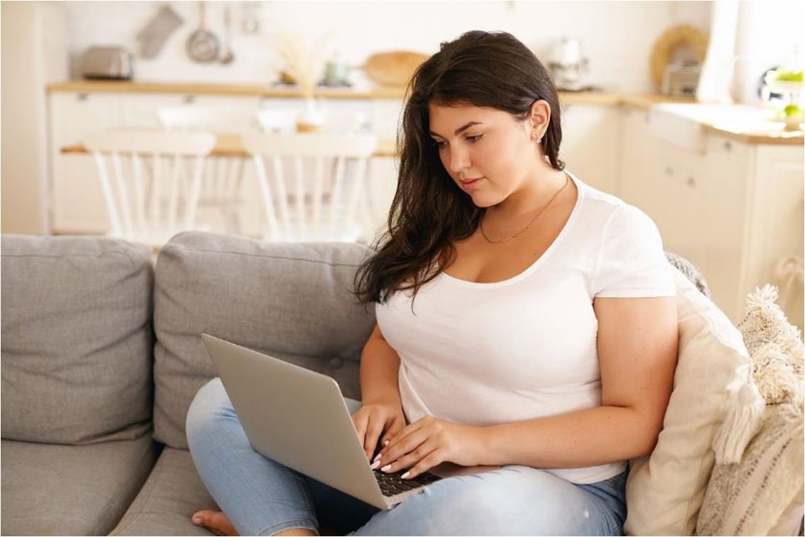 Woman sitting on her couch typing on her laptop