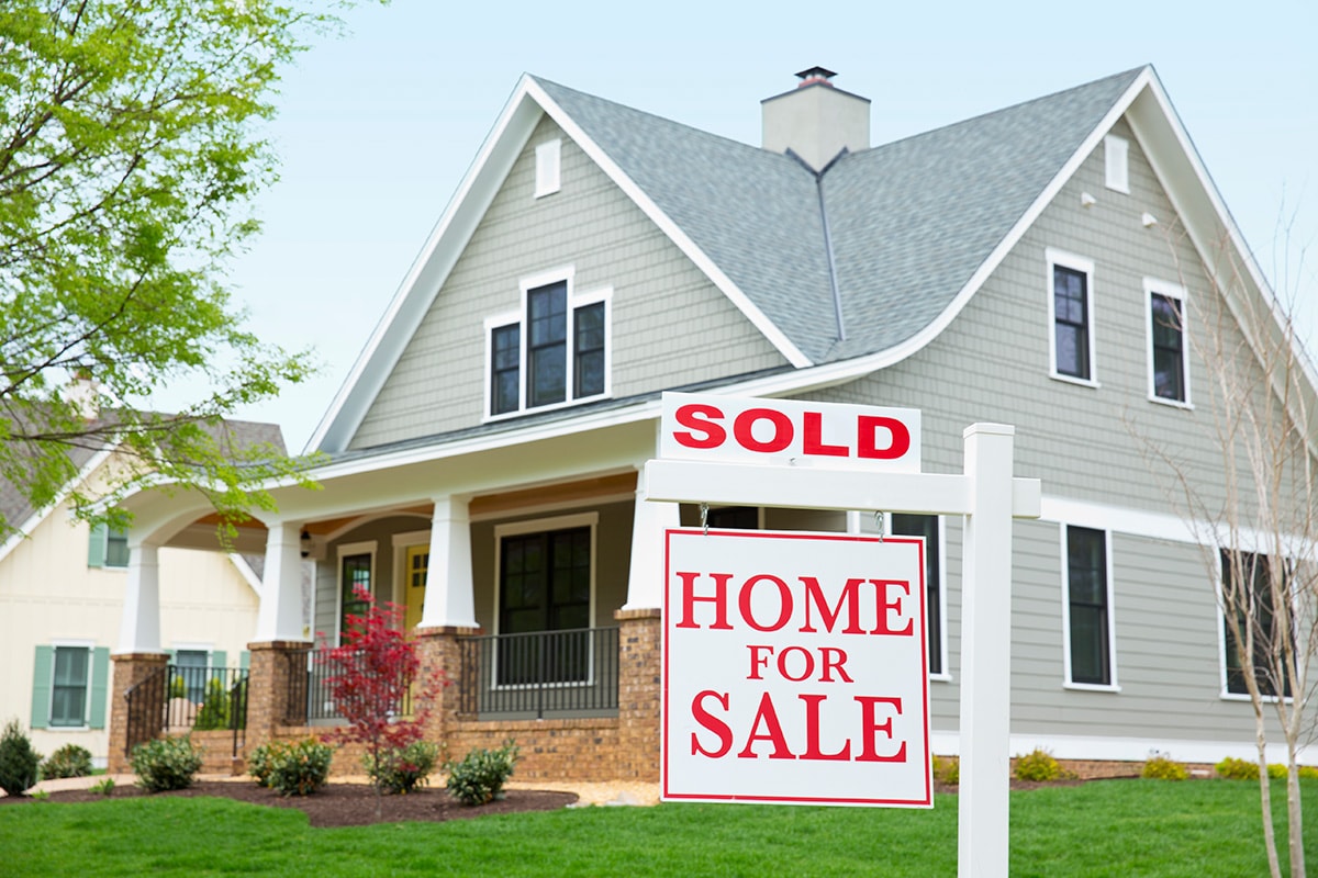A sold sign prominently displayed in front of a house, symbolizing successful real estate transactions and equal opportunity housing.