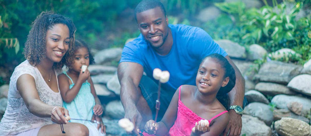 Family camping outdoors, enjoying smores on a campfire