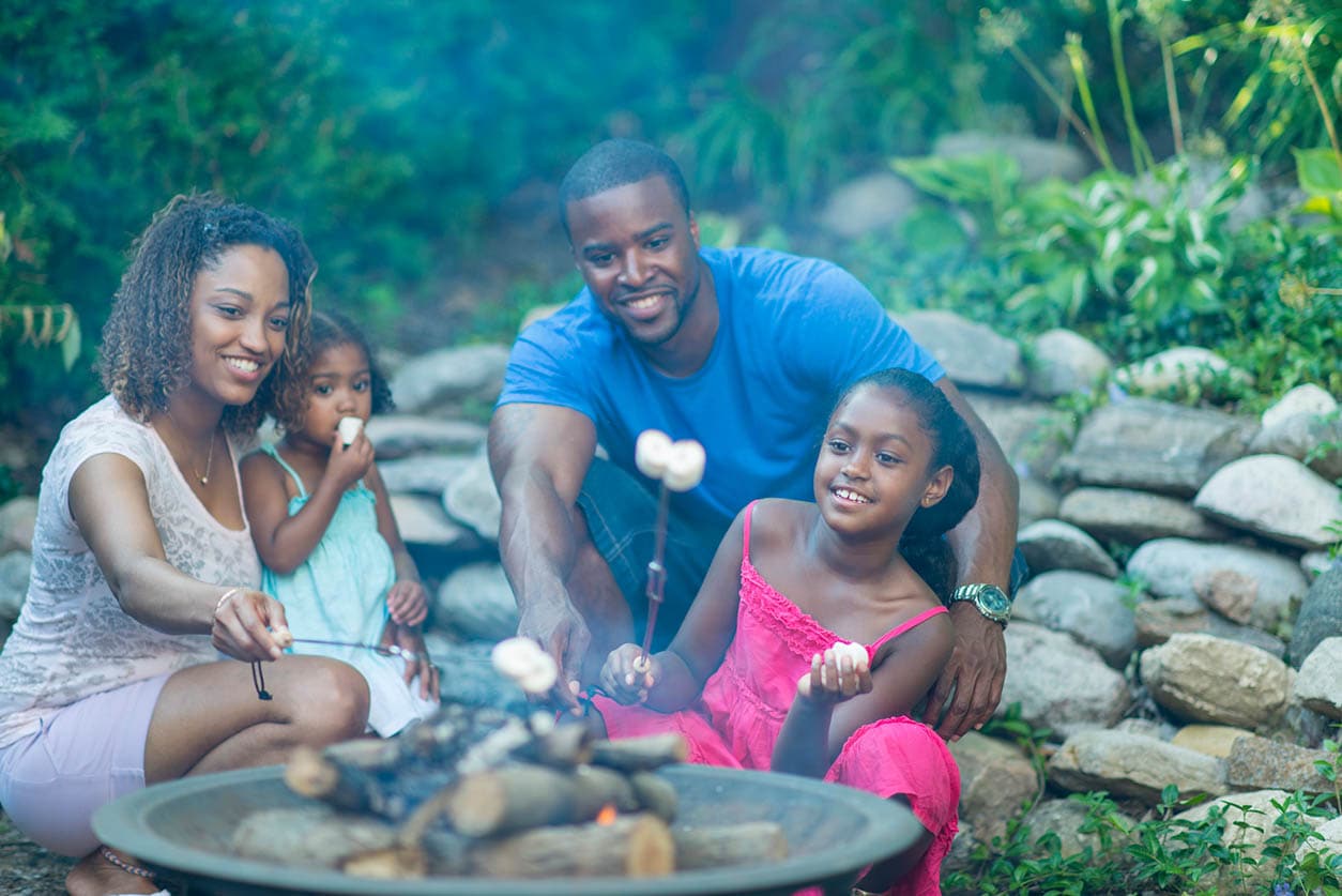 Family camping outdoors, enjoying smores on a campfire