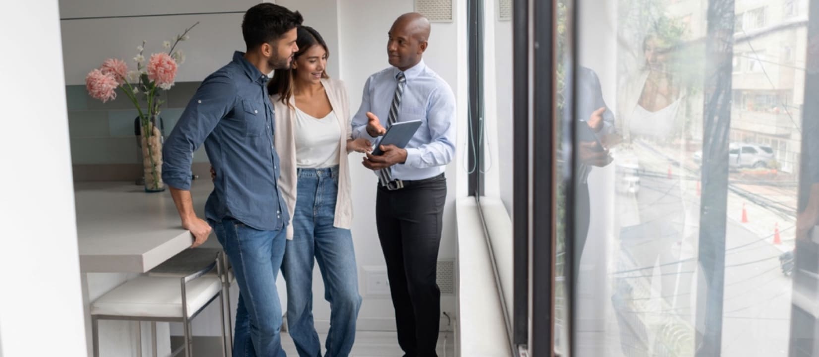 Man is talking to a couple in the kitchen in a new house