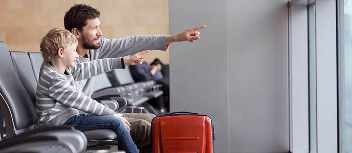 man and child sitting at an airport and pointing out of the window