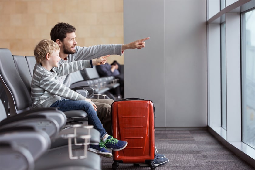 man and child sitting at an airport and pointing out of the window
