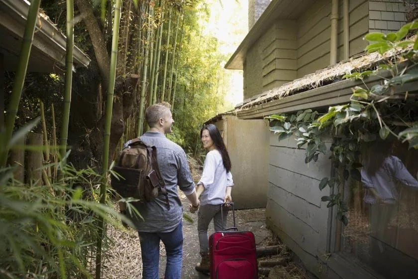 A couple strolls along a scenic path, carrying a suitcase, symbolizing their journey and travel adventures with credit cards.