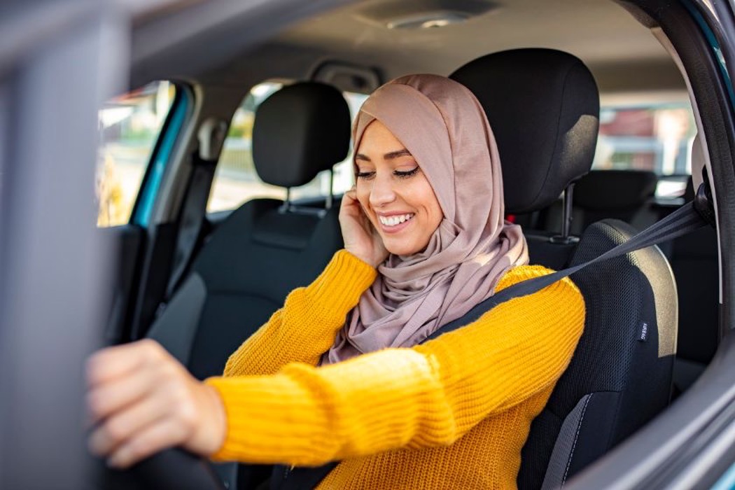 A woman speaks on her phone while sitting in her car