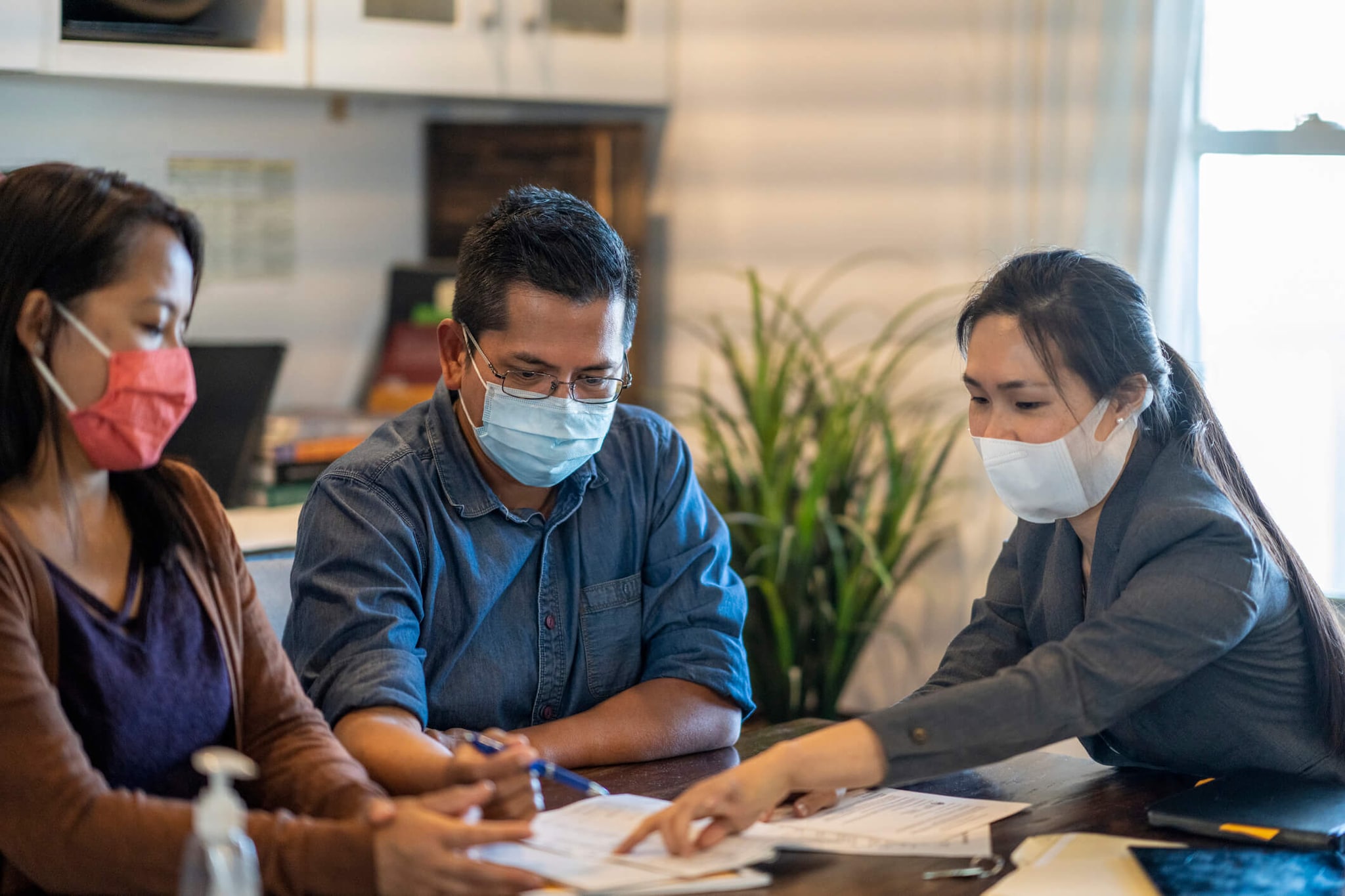 Two women and a man are sitting in the room looking through the paperwork