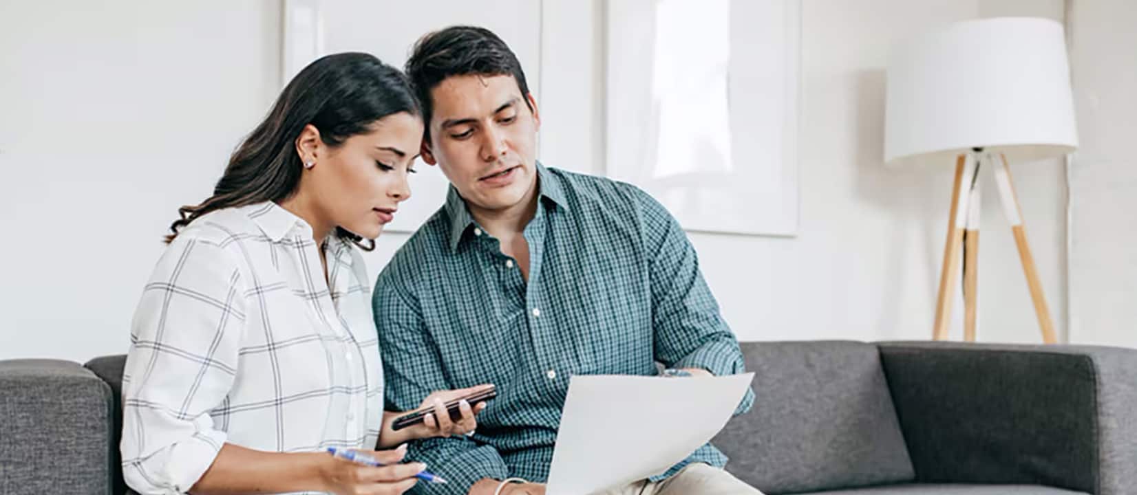 A couple reviews investment documents on a laptop, discussing growth versus value strategies for their financial future.