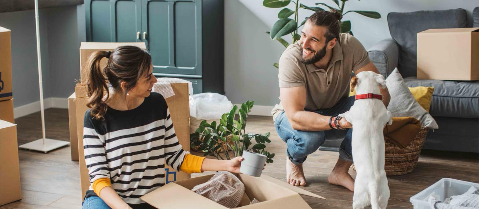 Man and woman are unpacking on the floor in the room with their dog