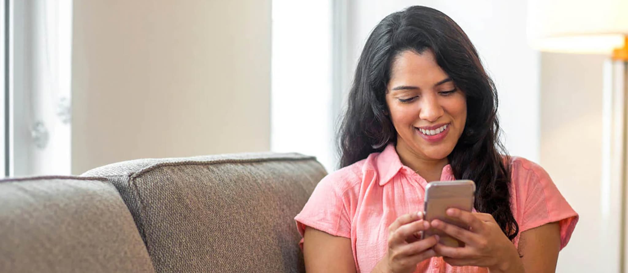 woman sitting on a couch and looking at her phone