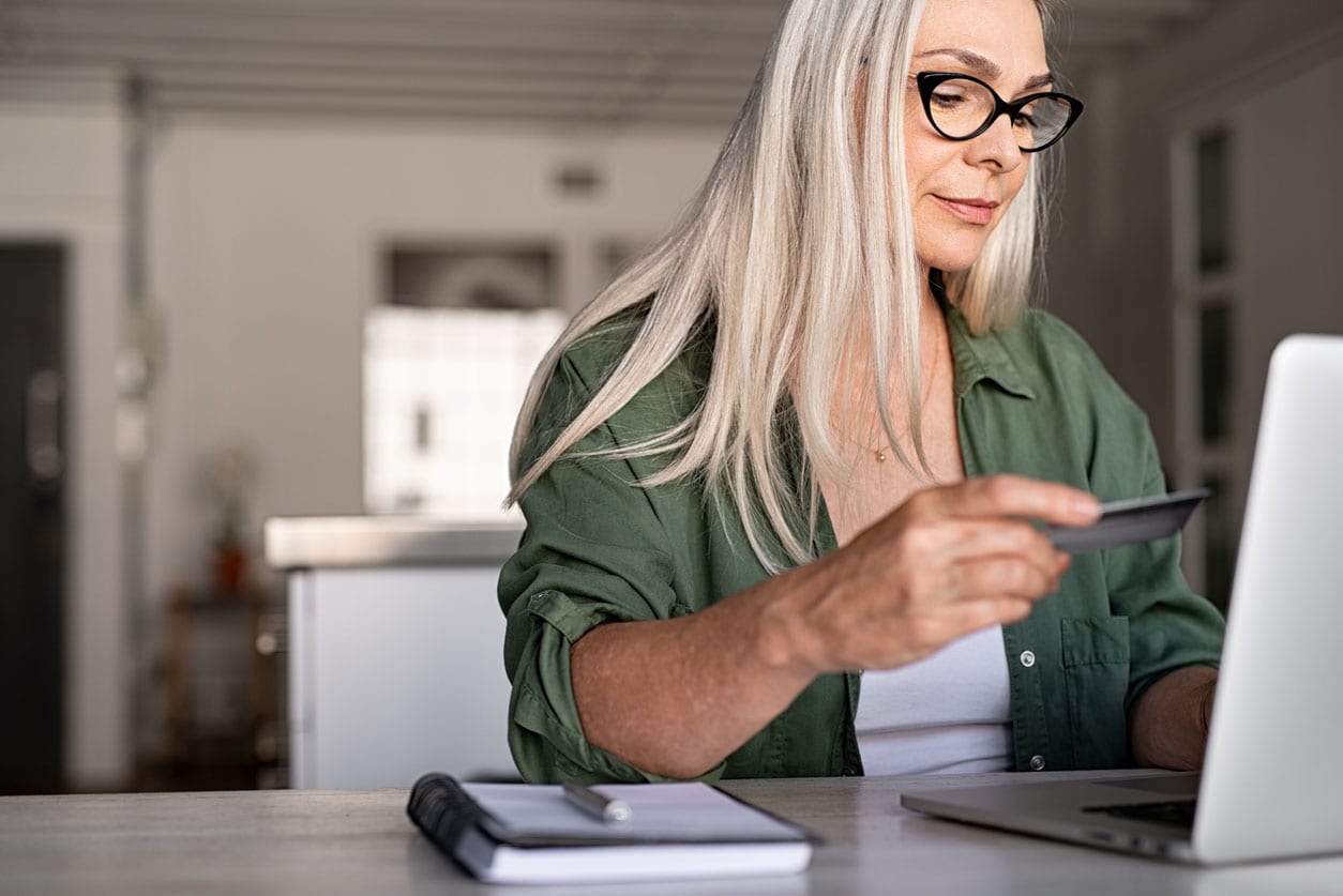 A woman holding a credit card, ready to make a purchase, with a focused expression on her face.