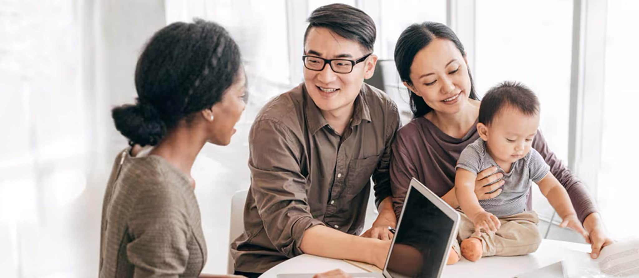 A family of three gathered around a table, engaged with a laptop, discussing home equity line of credit options.