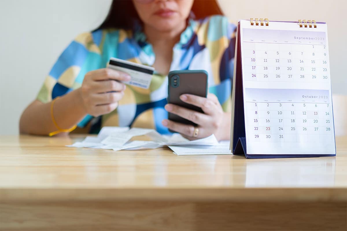 A woman holding a phone with a credit card in her hand.