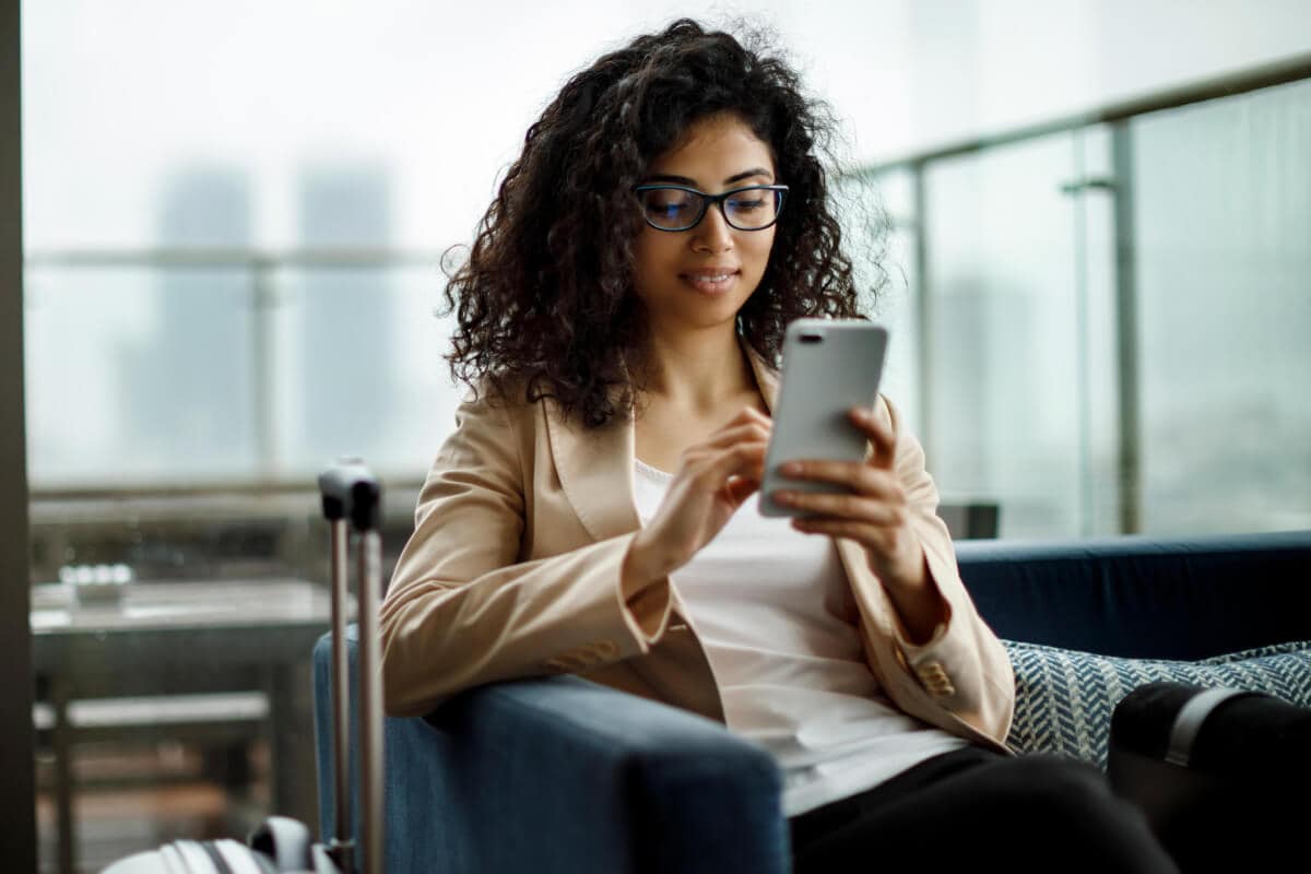A young person sitting on a couch applying for a credit card using their phone.