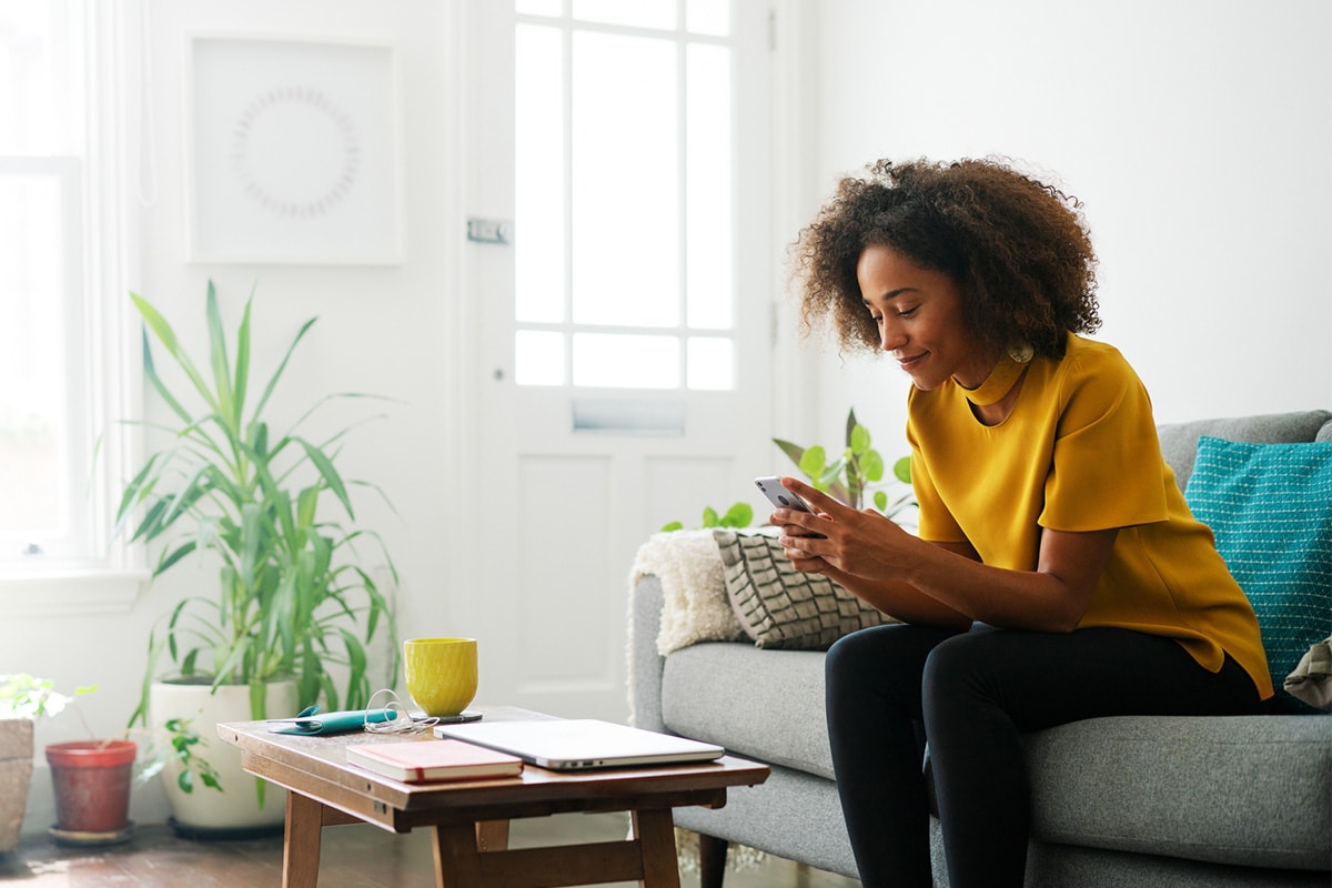 A person checking how to calculate home equity on her smart device sitting on a sofa
