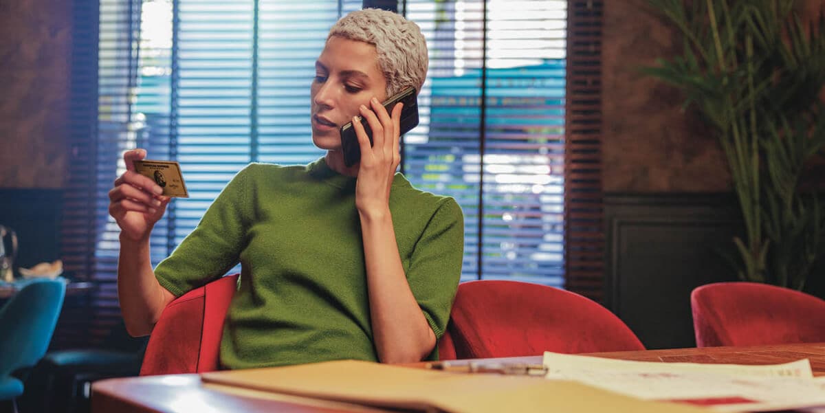A person looking at a credit card while making a phone call.