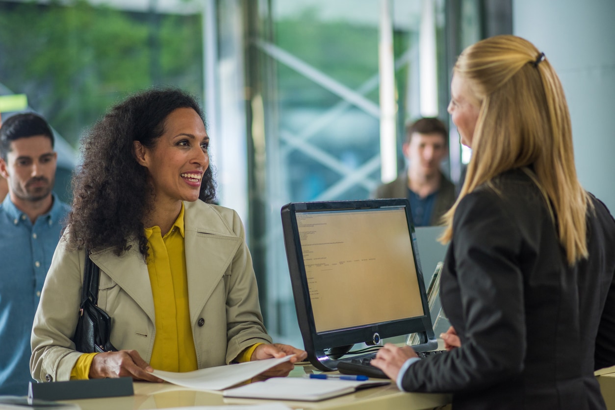Woman is talking to a woman behind the counter with a computer monitor