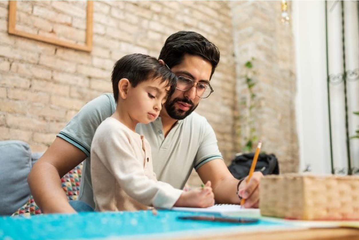 A man and boy writing at a table