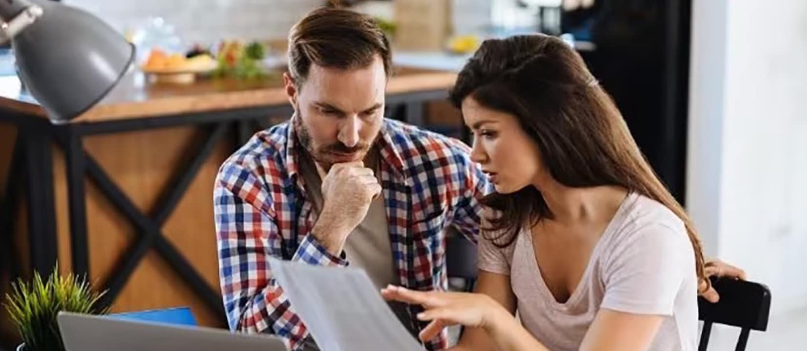 A man and woman collaborate at a table with a laptop, focusing on financial management strategies together.