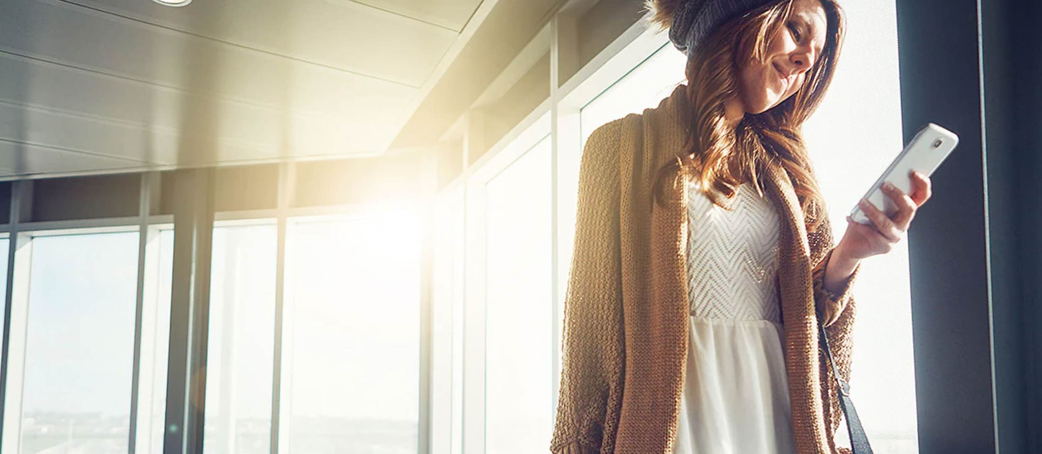 A traveler with luggage using her smartphone at the airport