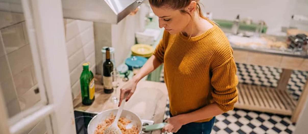 A person cooks in her kitchen