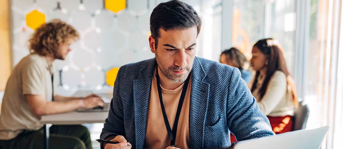 A person making notes from their laptop at a desk.