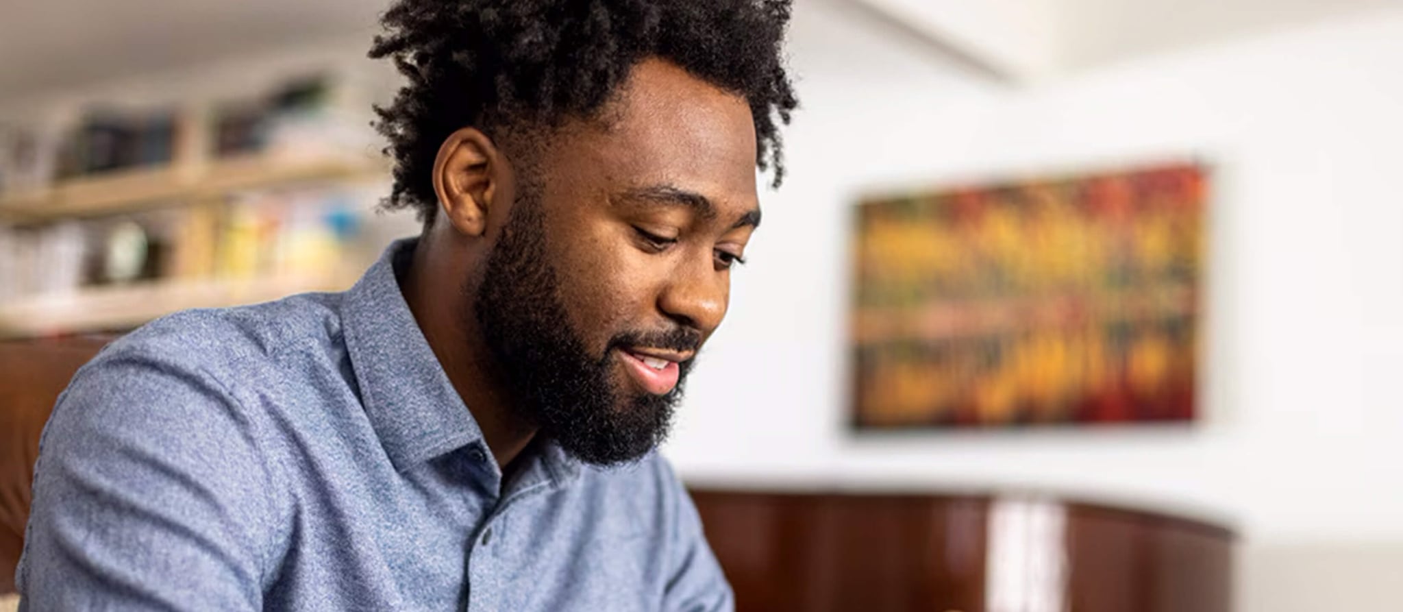 A man with a beard and laptop checks his phone, seeking guidance on beginner investment techniques.