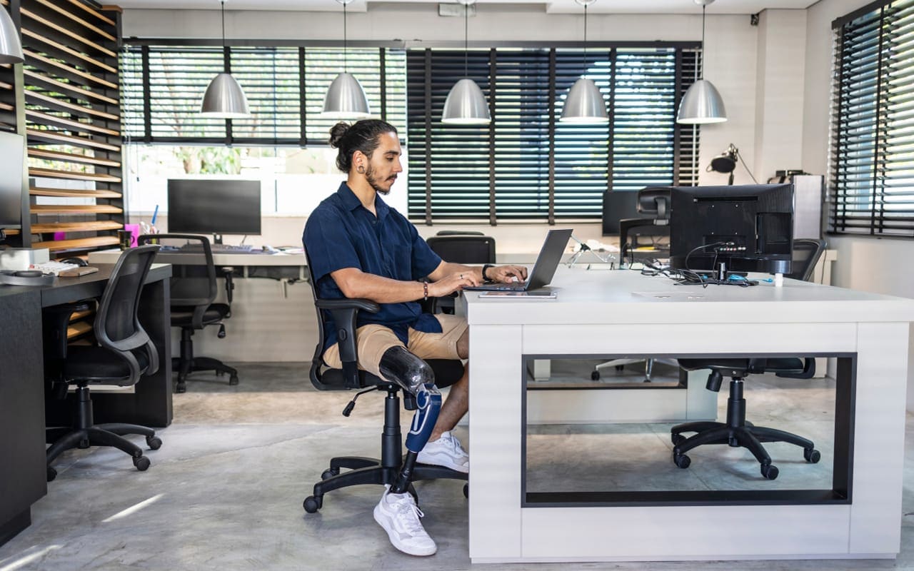 A professional image of a person sitting at a desk, using a laptop to open a new bank account.