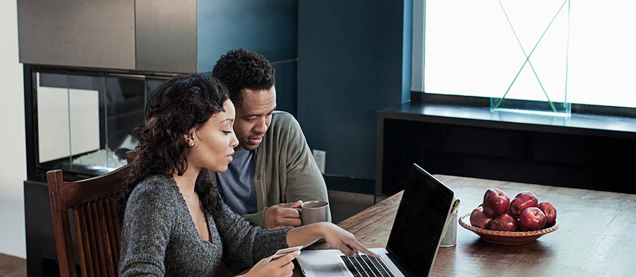 A man and woman seated at a table, engaged with a laptop, discussing financial matters related to inherited IRAs.