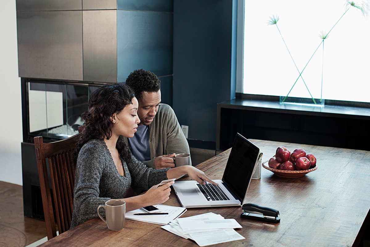 A man and woman seated at a table, engaged with a laptop, discussing financial matters related to inherited IRAs.