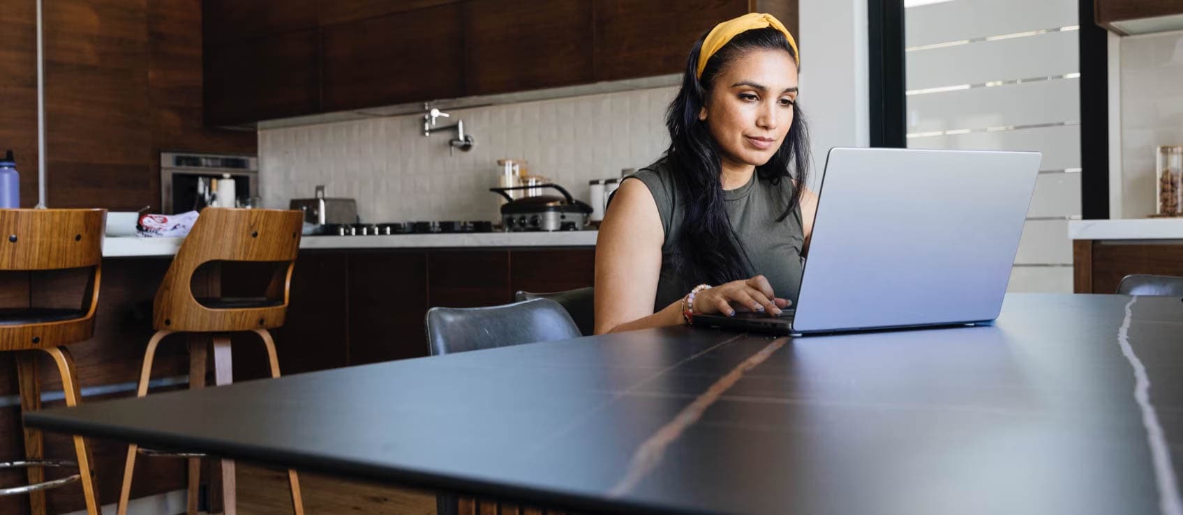 Woman is in the kitchen using her laptop