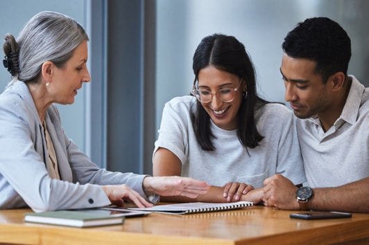 Couple is talking to a banker lady and looking through the paperwork on the table