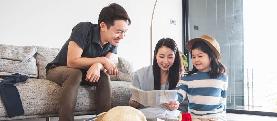 A family sitting on floor with suitcases and hat, ready for travel