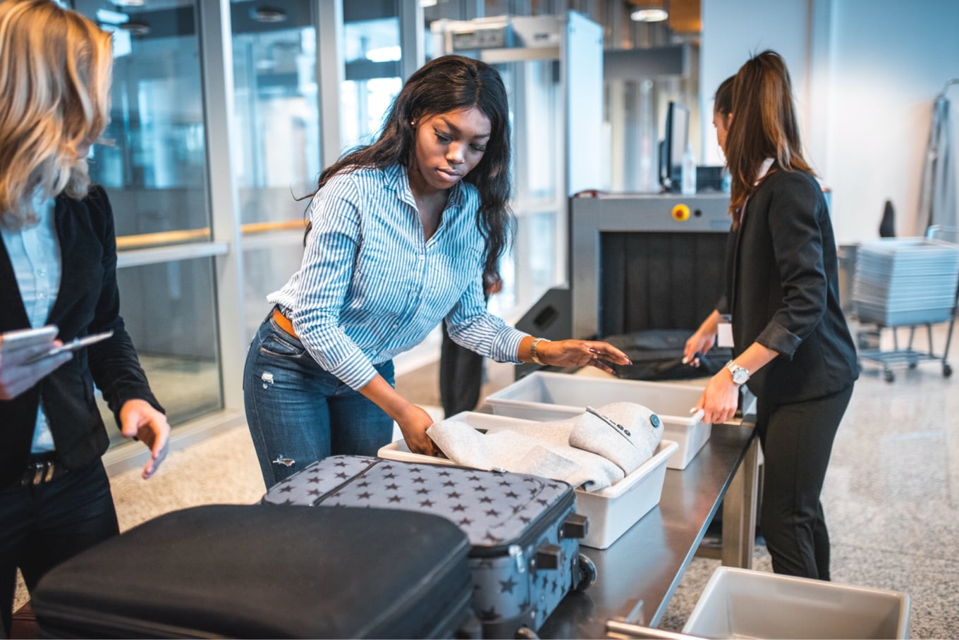 Woman is holding her luggage through TSA machine
